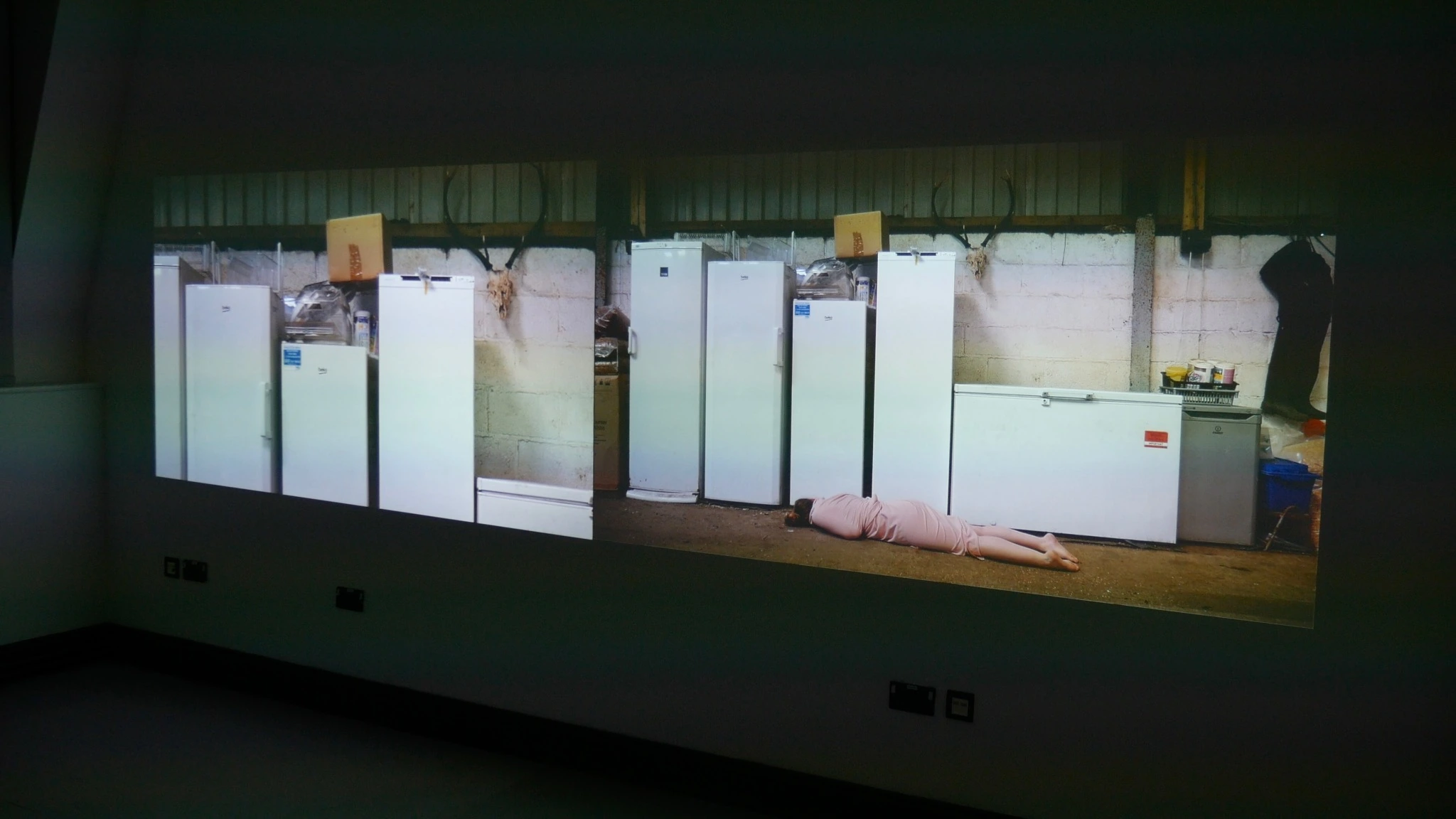 A panoramic installation projection showing a row of freezers